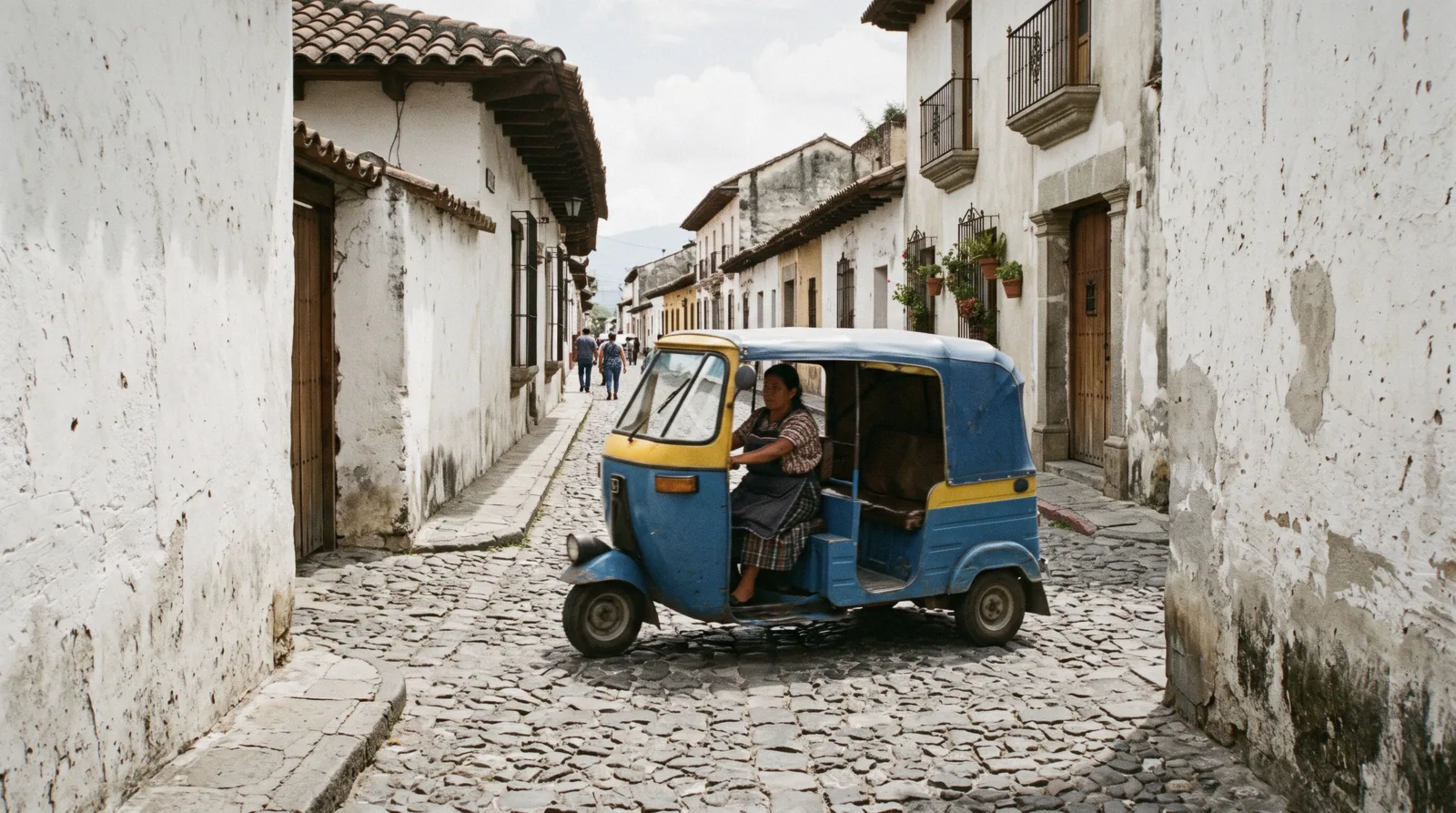 A tuk-tuk waiting on a cobblestone corner of the Antigua Guatemala grid